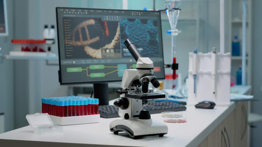 Close up of chemical microscope and medical research equipment in scientific laboratory. Liquid examination tool with glass lens and blood samples in vacutainers on professional desk
